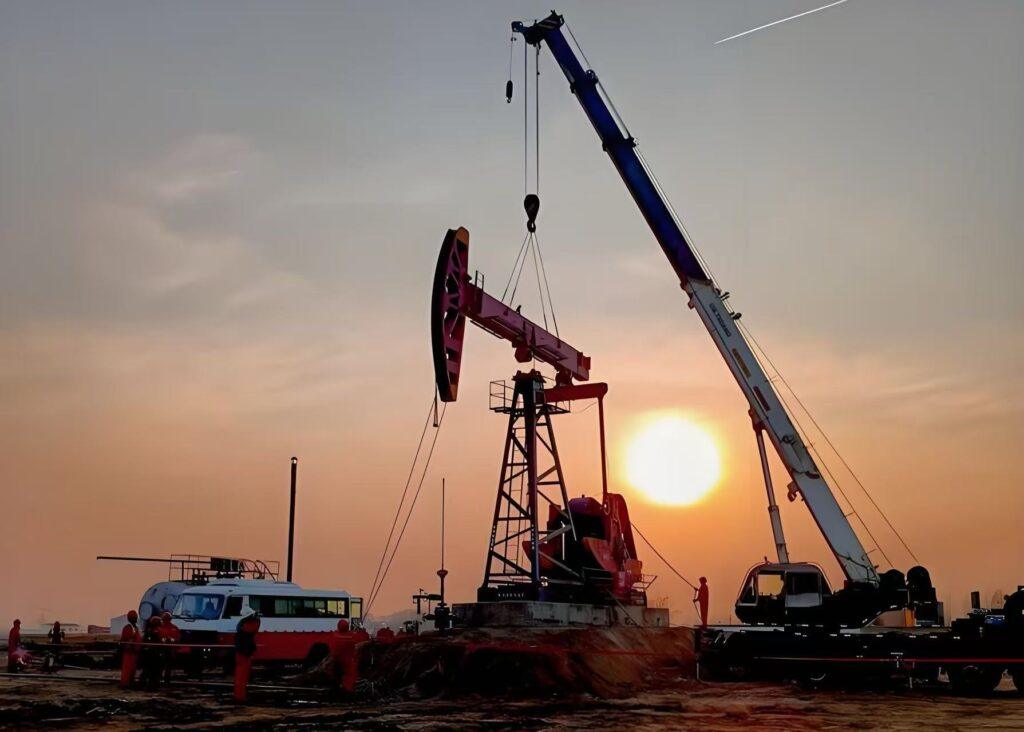 Oil and gas drilling site with pumpjack and crane at sunset, representing oilfield operations that rely on drilling fluid additives for wellbore stability and efficient drilling